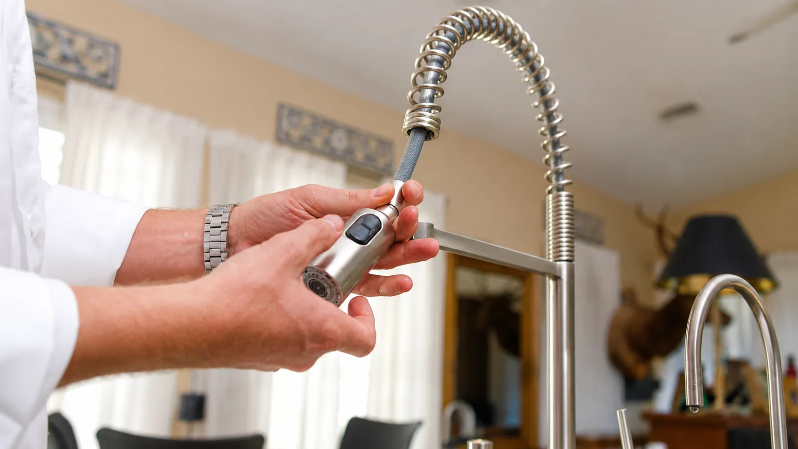 Plumber inspecting a pull down kitchen faucet sprayer