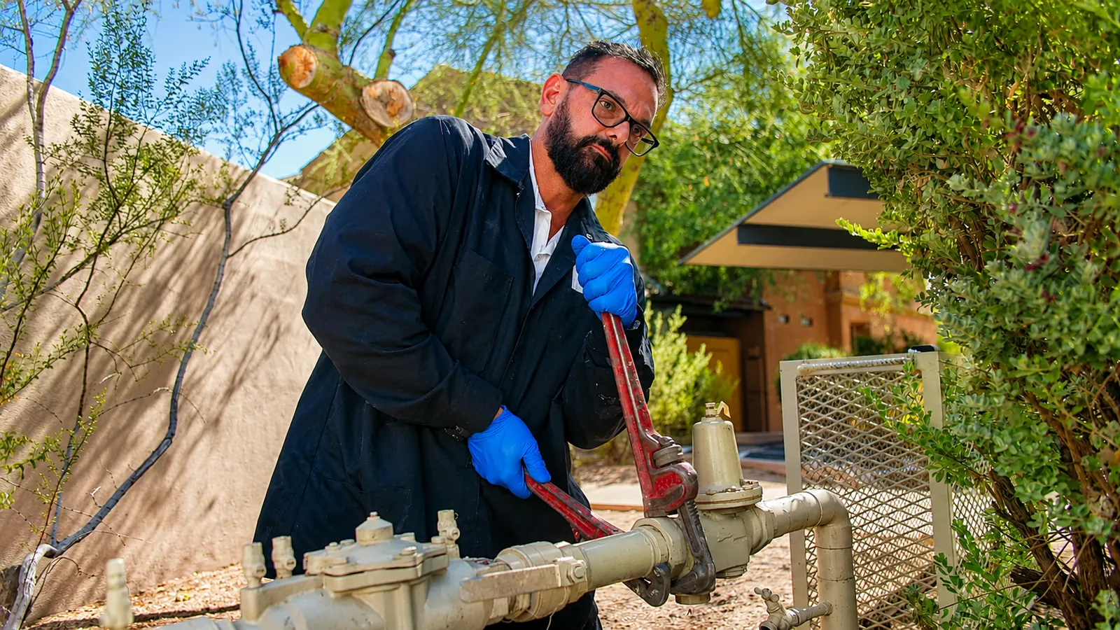 Plumber servicing an outdoor water line with a pipe wrench